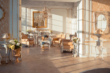 rich apartment interior with golden baroque decorations on the walls and luxury furniture. the room is flooded with the rays of the setting sun