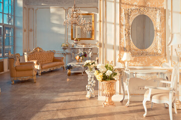rich apartment interior with golden baroque decorations on the walls and luxury furniture. the room is flooded with the rays of the setting sun