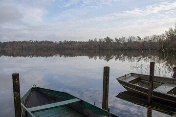 Obraz premium Fishermen boats in a lake during autumn time. Clouds reflecting on water.