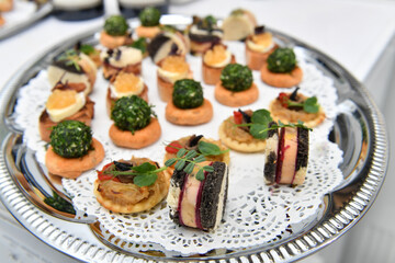 Catering. Colorful meat snacks with bread fruits and vegetables on a white plate.