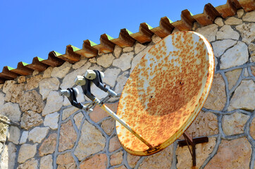 Rusty satellite TV radio internet wifi antenna on the wall of ancient house