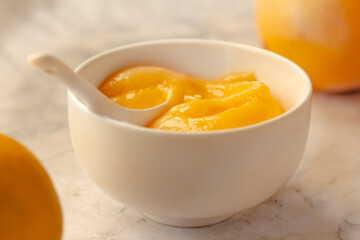 Composition with delicious Yellow lemons and Lemon curd in a sausepan white bowl on marble background