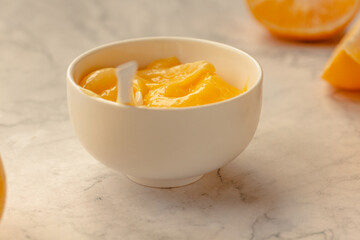 Composition with delicious Yellow lemons and Lemon curd in a sausepan white bowl on marble background