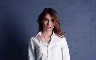 Obraz premium Portrait of young brunette woman in white shirt on black background