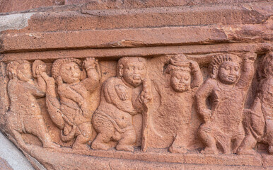Badami, Karnataka, India - November 7, 2013: Cave temples above Agasthya Lake. Closeup of restone sculpture of row of small human figures carrying a beam of the building.