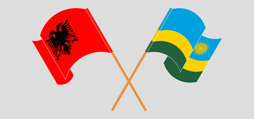 Crossed and waving flags of Albania and Rwanda
