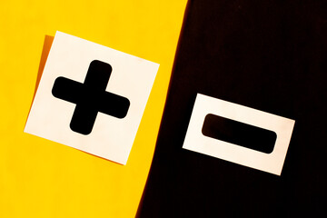 Symbols of black color plus and minus on black and yellow background. Abstraction