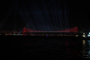 Obraz premium Fireworks over Istanbul Bosphorus during Turkish Republic Day celebrations. Bosphorus Bridge with red lighting and lasers at night time.