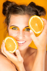 Frau mit Orange Obst in der Hand gelb weiße Zähne Make Up braune Haare
