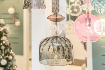 A group of switched-off ceiling chandeliers with a transparent glass cover on the background of a...