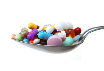 Spoonful of mixed pills, tablets and capsules isolated against a white background. Self medication substance abuse concept