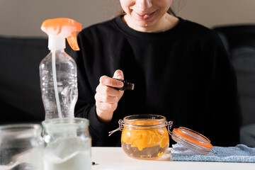 Millennial girl doing diy cleaning spray at home with vinegar, soda and lemon. Zero waste...