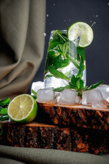 Mojito cocktail on a dark background. Wooden stand. Ice and mint.