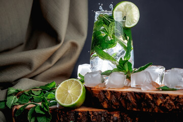 Mojito cocktail on a dark background. Wooden stand. Ice and mint.