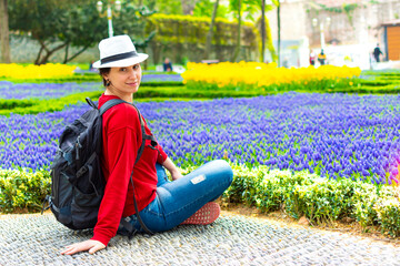 Young tourist woman seating in park against colorful flowers during Tulip festival in Istanbul, Turkey.