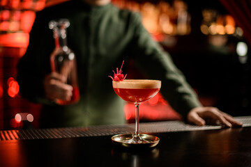 view of beautiful glass with red foamy alcoholic drink decorated with flower on bar