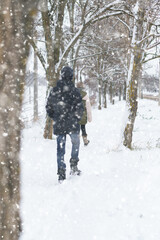 two people walk on a snow-covered path in winter, a teenage boy and a girl, a snowstorm