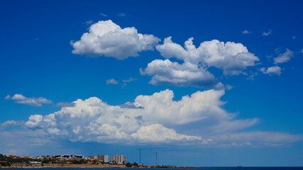 Orihuela Costa, Alicante, Spain - July, 2020: View to blue big white clouds on blue sky above coast. High quality photo