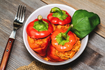 red pepper stuffed with meat and bulgur in a white plate on a wooden table