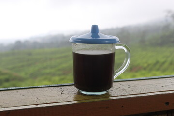 The black coffee in the tea garden is shrouded in mist. a cup of black coffee in a mountainous...