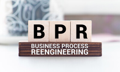 BPR - Business process reengineering - acronym on wooden cubes on columns of numbers background.