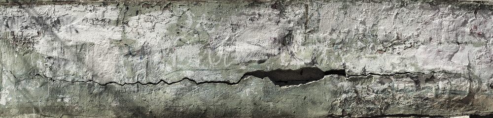 Obraz na płótnie Canvas Peeling wall. Panorama of a concrete wall with old cracked flaking paint. Weathered rough painted surface with patterns of cracks and peeling. Wide panoramic texture for design background