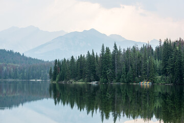 Waterscape in the Canadian Rockies with reflections of trees and mountains in the background.