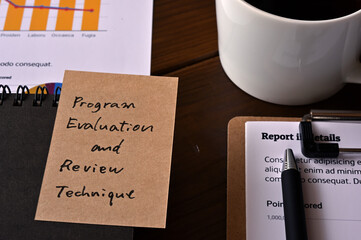 There's a notebook,and a laptop with a sticky note stuck to it that says Program Evaluation and Review Technique.