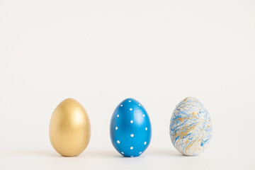 Three Easter golden decorated eggs on white background. Minimal easter concept. Happy Easter card with copy space for text. Top view, flatlay.