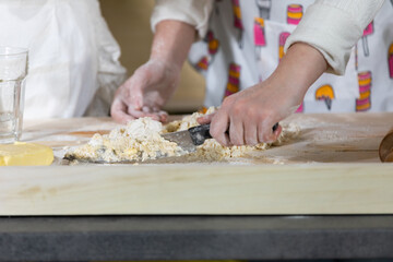 Mum stirs the dough with a kitchen knife and her five-year-old daughter does it with a spoon. Mother and baby do the dough together in the kitchen.