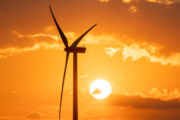 wind turbine during sunset under partly cloudy skies