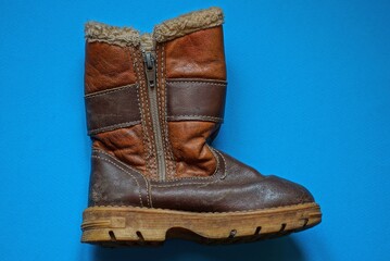 one old brown leather boot with zip and fur lies on a blue table