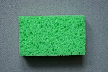 Fototapeta na wymiar one green foam sponge lie on a gray table