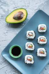 Sushi rolls with salmon, avocado and soy sauce on a plate. Top view, copy space.