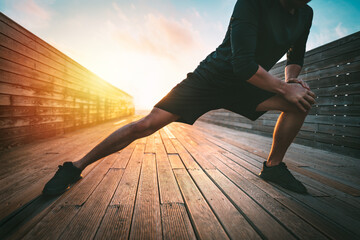 Fitness man stretching legs before workout outdoors. Warming up before running. Sport and healthy lifestyle.