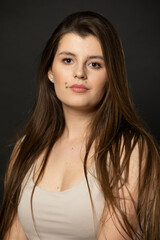 Naklejka premium Portrait of an attractive young girl who looks into the camera with beautiful long dark brown hair.