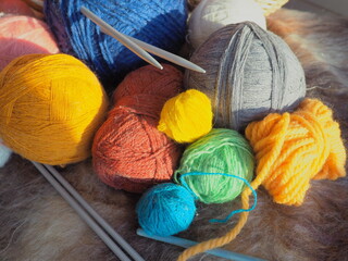 Knitting a scarf or sweater from gray, blue, white and orange yarns. Hanks of woolen and acrylic...