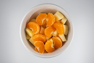 Bol de macedonia de frutas con trozos de mandarina y manzana.