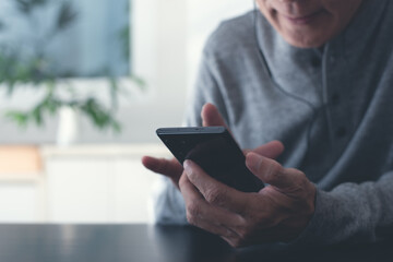 Casual man with earphones listening to podcast app on mobile phone at home