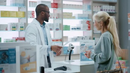 Pharmacy Drugstore Checkout Counter: Black Male Pharmacist Explains Use and Manual for Prescription Medicine Beautiful, Senior Female Customer Paying Using Contactless Credit Card to Terminal - Powered by Adobe