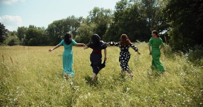  Four fashionable girls running on a green meadow