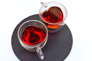Two transparent heart-shaped cups with tea on the white background. Top view.