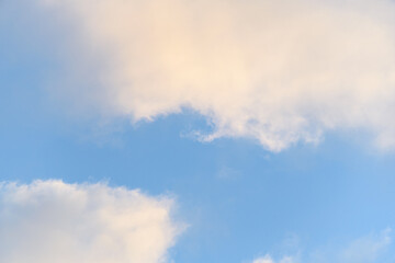 Late afternoon cloudscape, glowing clouds against a blue sky, as a nature background
