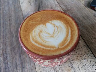 a cup of cappuccino with latte art on wood table. top angle view 