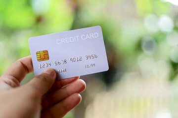 A woman holding a silver credit card, she uses her credit card for online shopping, credit card concept.