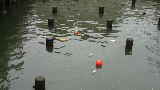 Trash flowing in water in Manhattan. Dirty and polluted Water in USA. Orange Ball on Water in Port