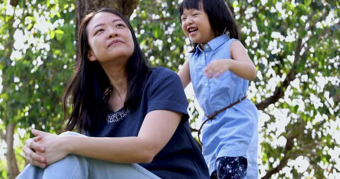 4K Video Slow motion Asian little daughter hug her mom with smile in the park. Concept for family relationship and relaxing time.