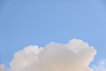 Late afternoon cloudscape, glowing clouds against a blue sky, as a nature background
