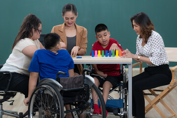 Group of special students in classroom, a down syndrome girl, two handicapped boys and cute Asian...