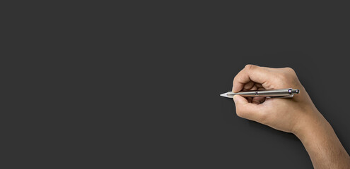 Person's hand holding a pen and about to write, Isolated on a dark gray background and clipping path.